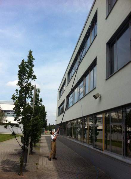 Reinigung eines Fensterbandes an einem Bürogebäude mit Reinstwasser und Teleskopstange, ohne Leiter